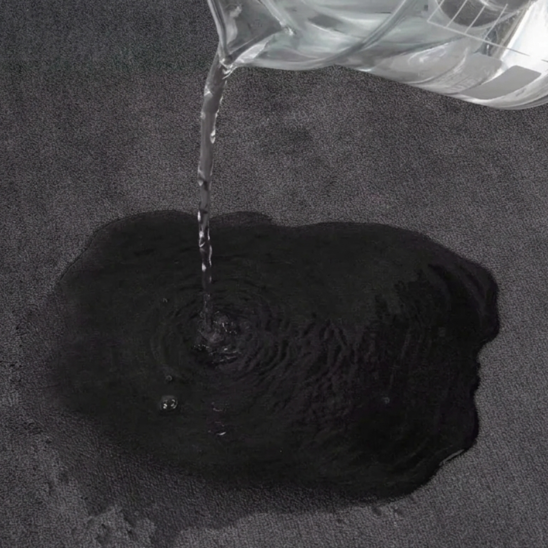 Clear liquid being poured onto a gray bath mat
