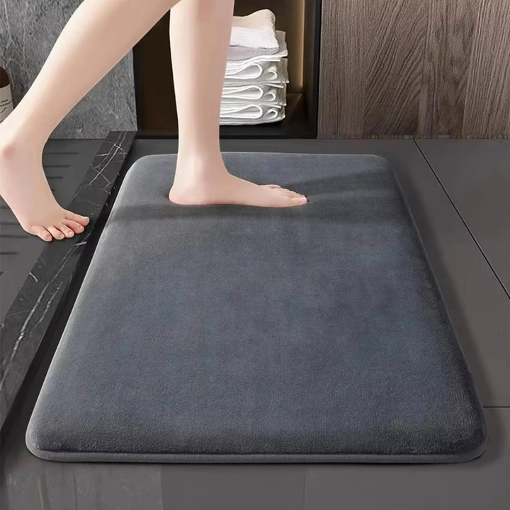 Person stepping onto a gray bath mat in a bathroom setting
